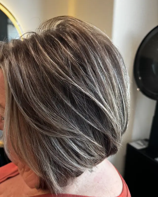 After: bright silver-blonde highlights on a rich brown base, cut into a stacked bob