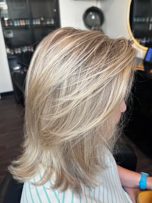 Bright, blended blonde highlights on a long, layered cut, seen from the side